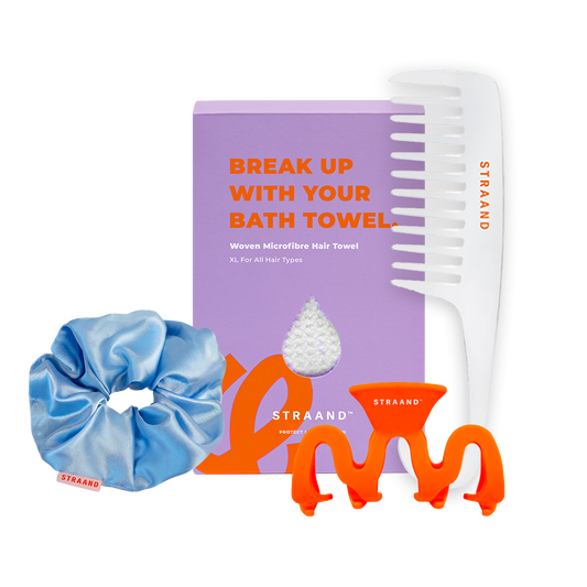 A collection of hair care accessories including a purple hair towel, a white and orange detangler comb, a blue satin scrunchie, and an orange claw clip, all arranged against a white background.