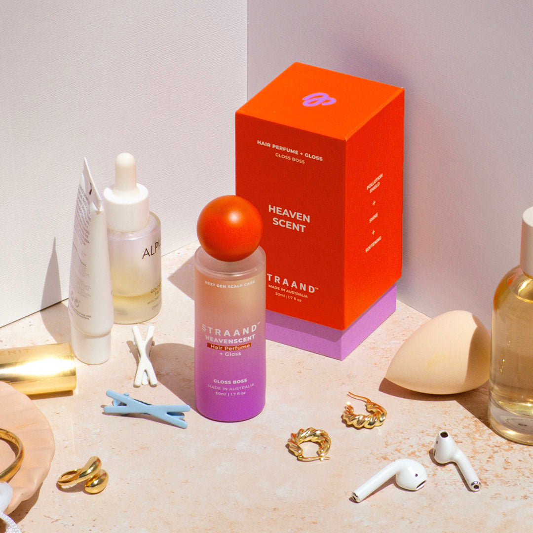 Hair perfume on a bathroom bench with gold earrings