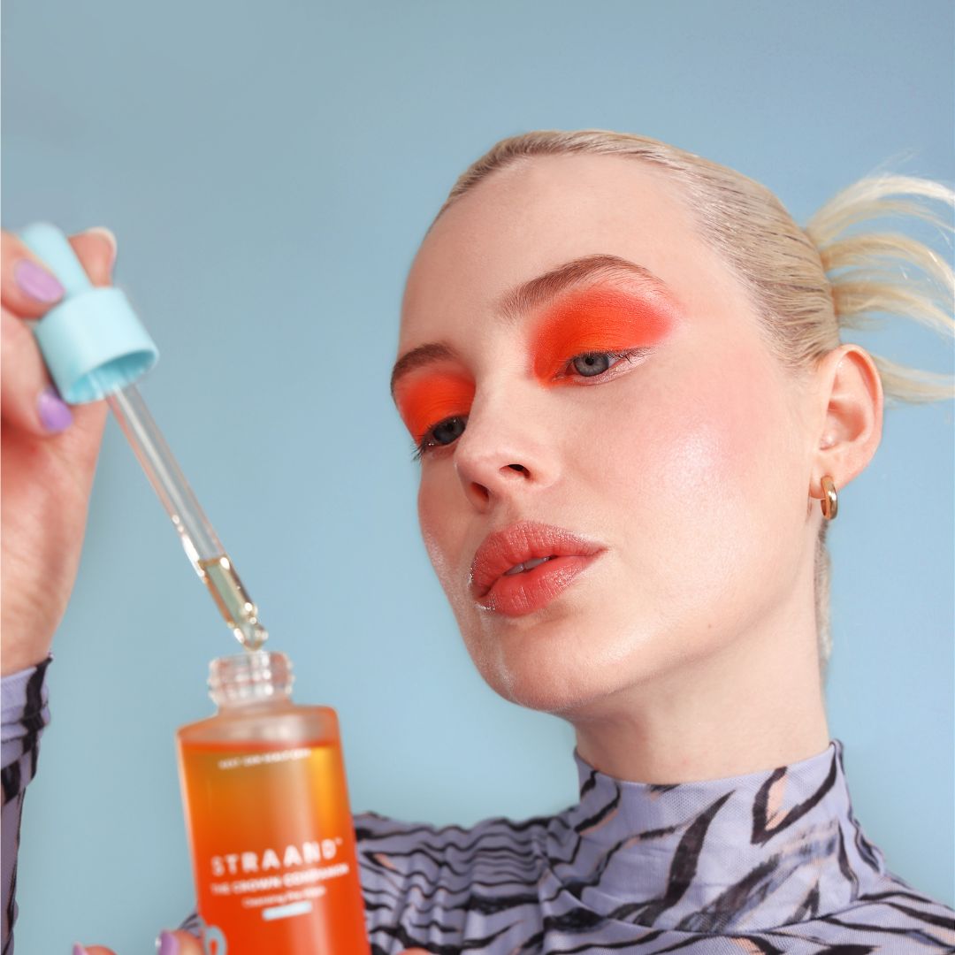 Woman with dramatic makeup testing a hair oil that helps with hair growth