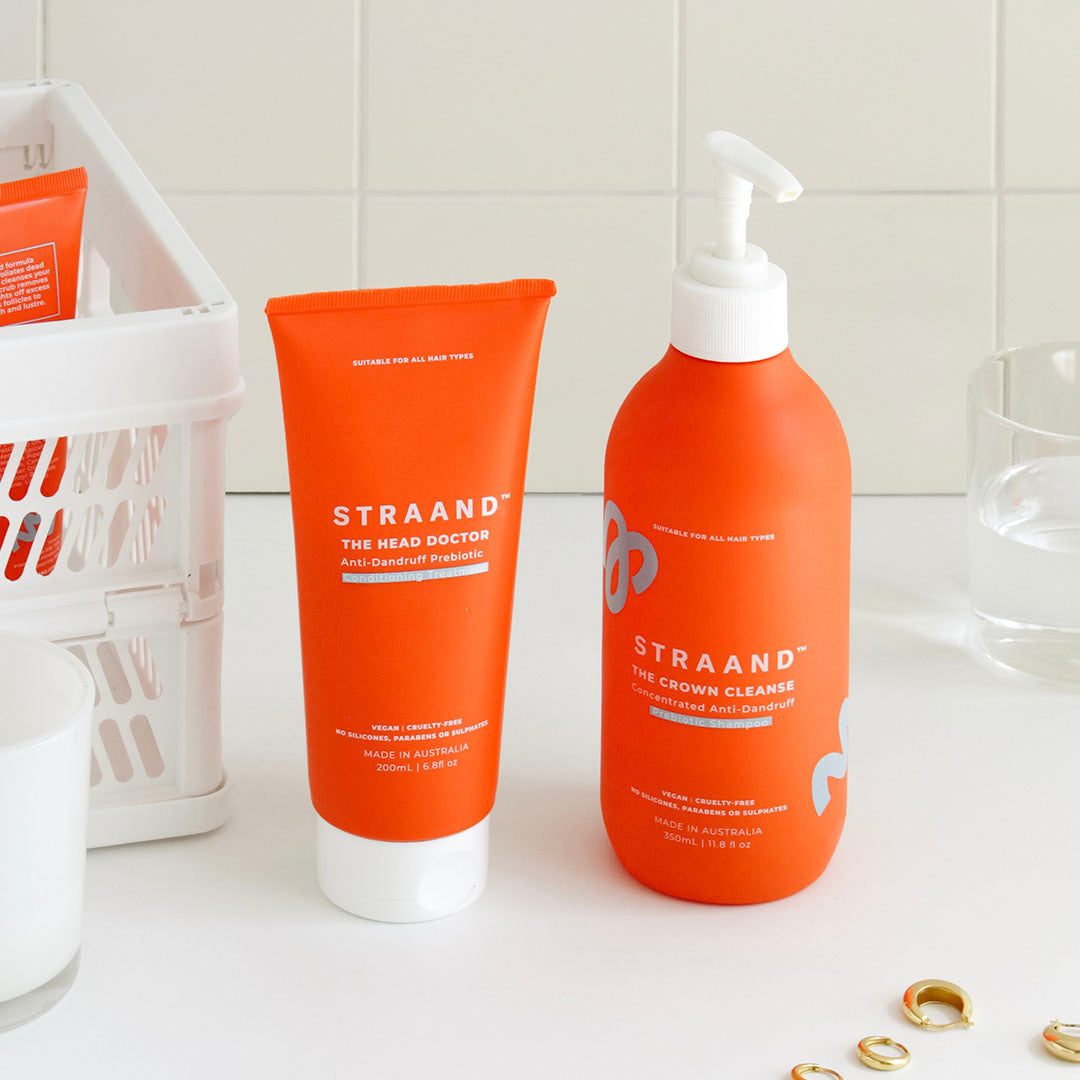 Shampoo and conditioner in orange bottles shown on a bathroom bench