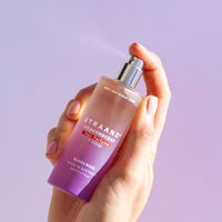 Hand holding a hair perfume in a beautiful purple glass bottle