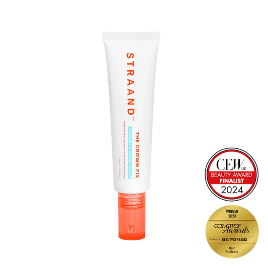 A bottle of 'The Crown Fix Scalp Serum' by STRAAND with a white body and red cap. It has text on the bottle and two seals indicating it as a Beauty Award Finalist and a Consumer Choice Award Winner.