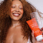 Woman with dark curly hair using the shower comb