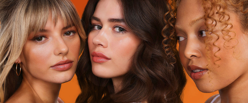 Three women with different hair colors against an orange background
