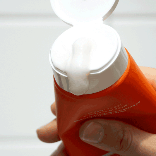 Squeezing the salt scalp scrub out of an orange tube to show the white liquid within